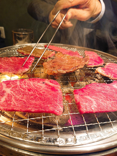 Raw and grilled beef on a barbequeue stove