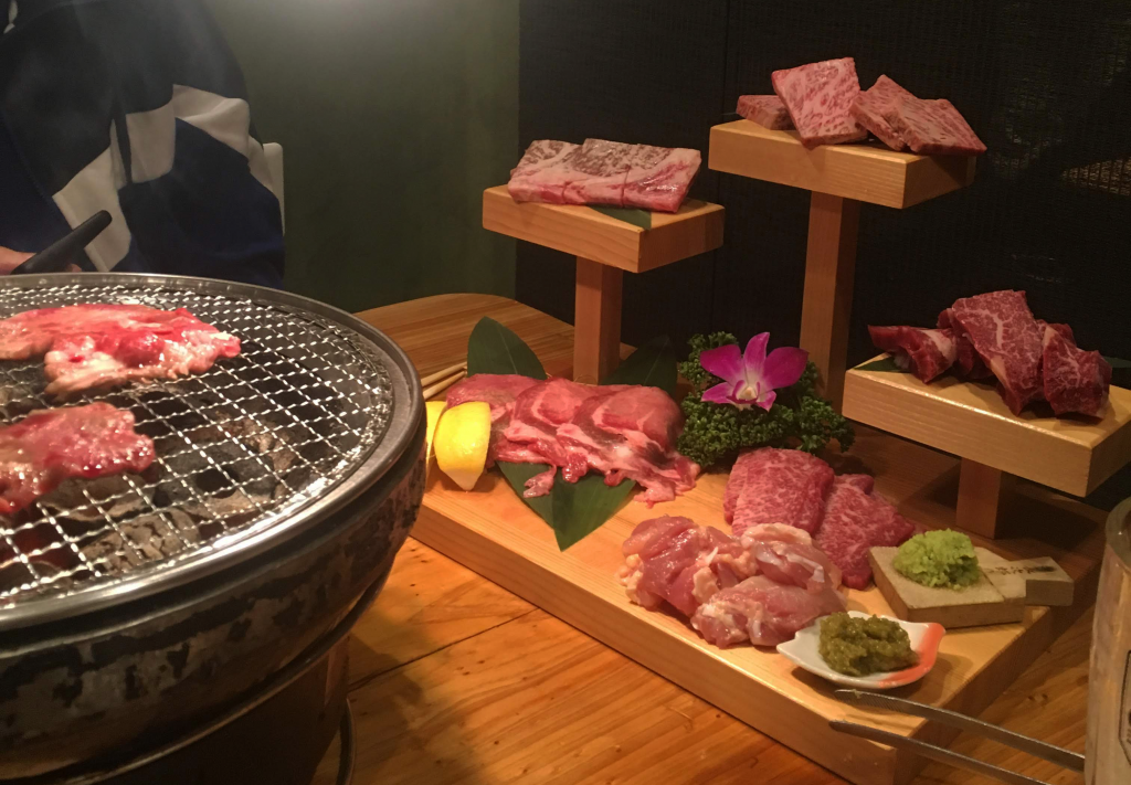 A choice selection of various kinds of meat next to a BBQ grill