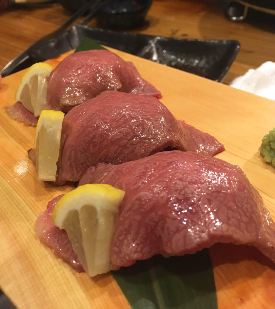 Sushi beef, half grilled beef slices on rice with a wedge of lemon on the side.